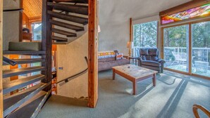 Un vaste espace de vie agrémenté d’un escalier en bois, d’un canapé, d’une table basse et d’un fauteuil en cuir.