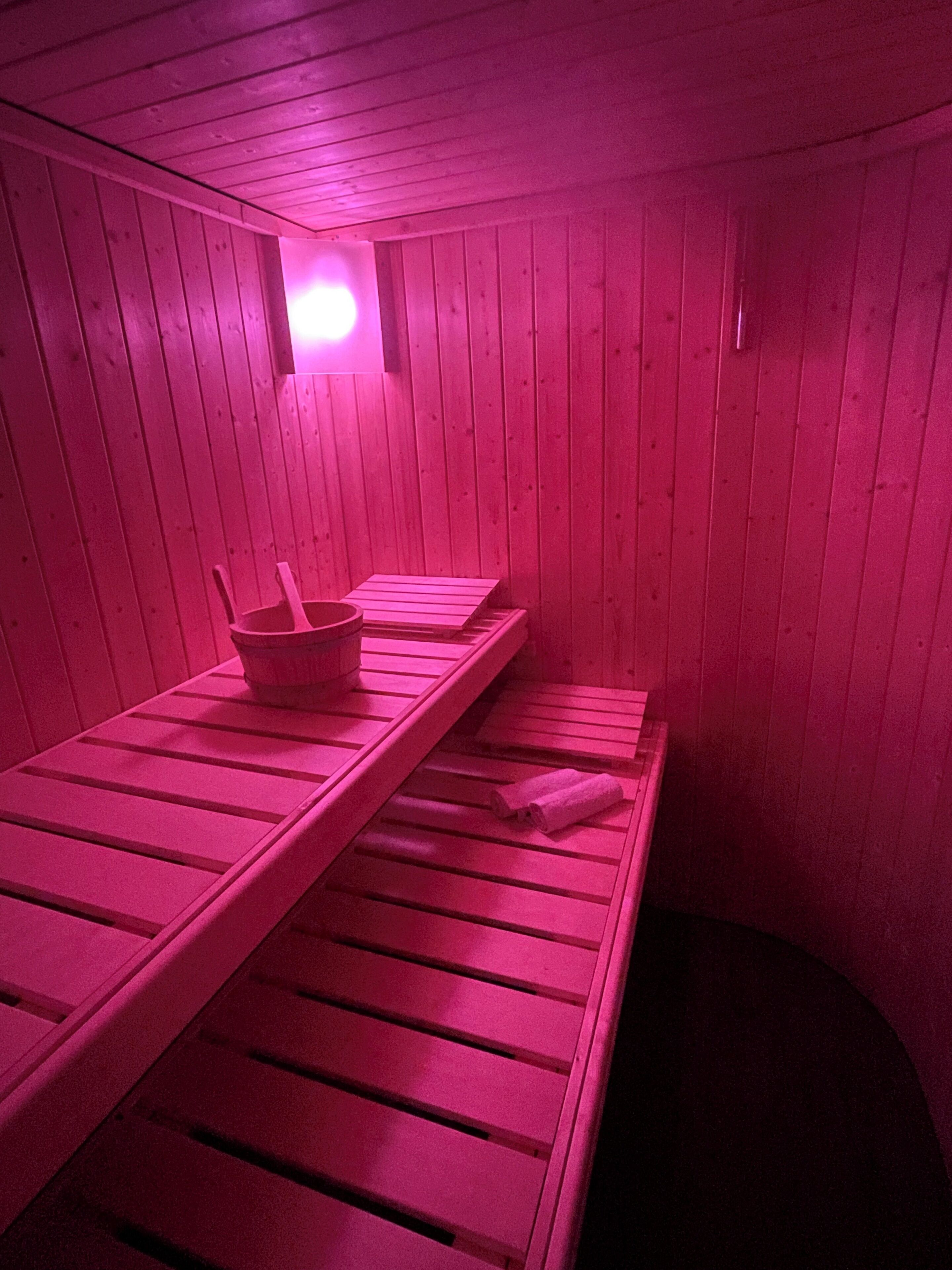 A sauna with wooden benches and a bucket.