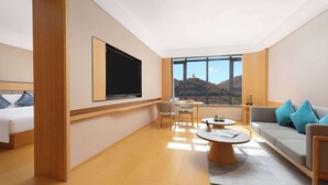 Una habitación de hotel moderna con un ventanal grande, un televisor de pantalla plana, un sofá, una mesa de comedor y una cama.