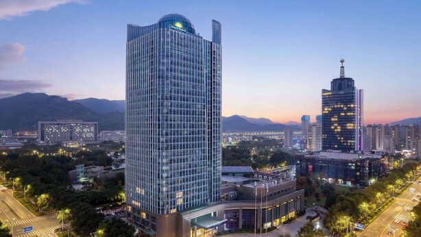 A high-rise hotel with a modern glass facade, surrounded by urban infrastructure and greenery. - Days Hotel By Wyndham Taizhou Sanmen (Taizhou)