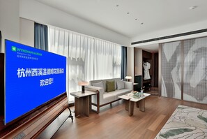 A modern living room with a flat-screen TV, a sofa, a coffee table, and a patterned rug. - Wyndham Garden Hangzhou Xixi (Hangzhou)