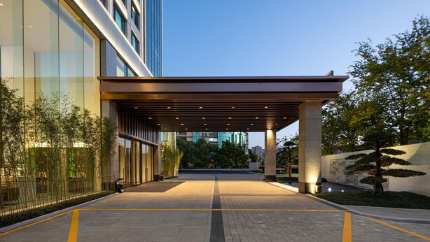 A modern hotel entrance with a covered walkway, glass facade, and landscaped area. - Wyndham Garden Hangzhou Xixi (Hangzhou)