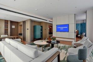 Un vestíbulo de hotel moderno con una zona de estar, una pantalla de televisión y un armario de madera.