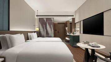 A hotel room with two beds, a TV, a desk, and a bathroom.