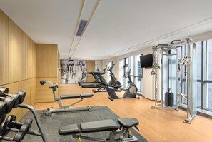 Un gimnasio con equipo de ejercicio variado, incluyendo cintas de correr, elípticas y pesas libres.