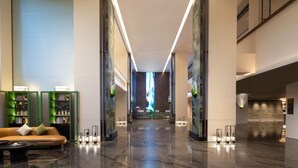 A modern hotel lobby with a reception desk, a sofa, and green-framed shelves. - Wyndham Garden Hangzhou Xixi (Hangzhou)