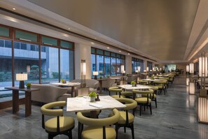 Un hall de hotel espacioso con varias zonas de estar, amplias ventanas y mobiliario moderno.