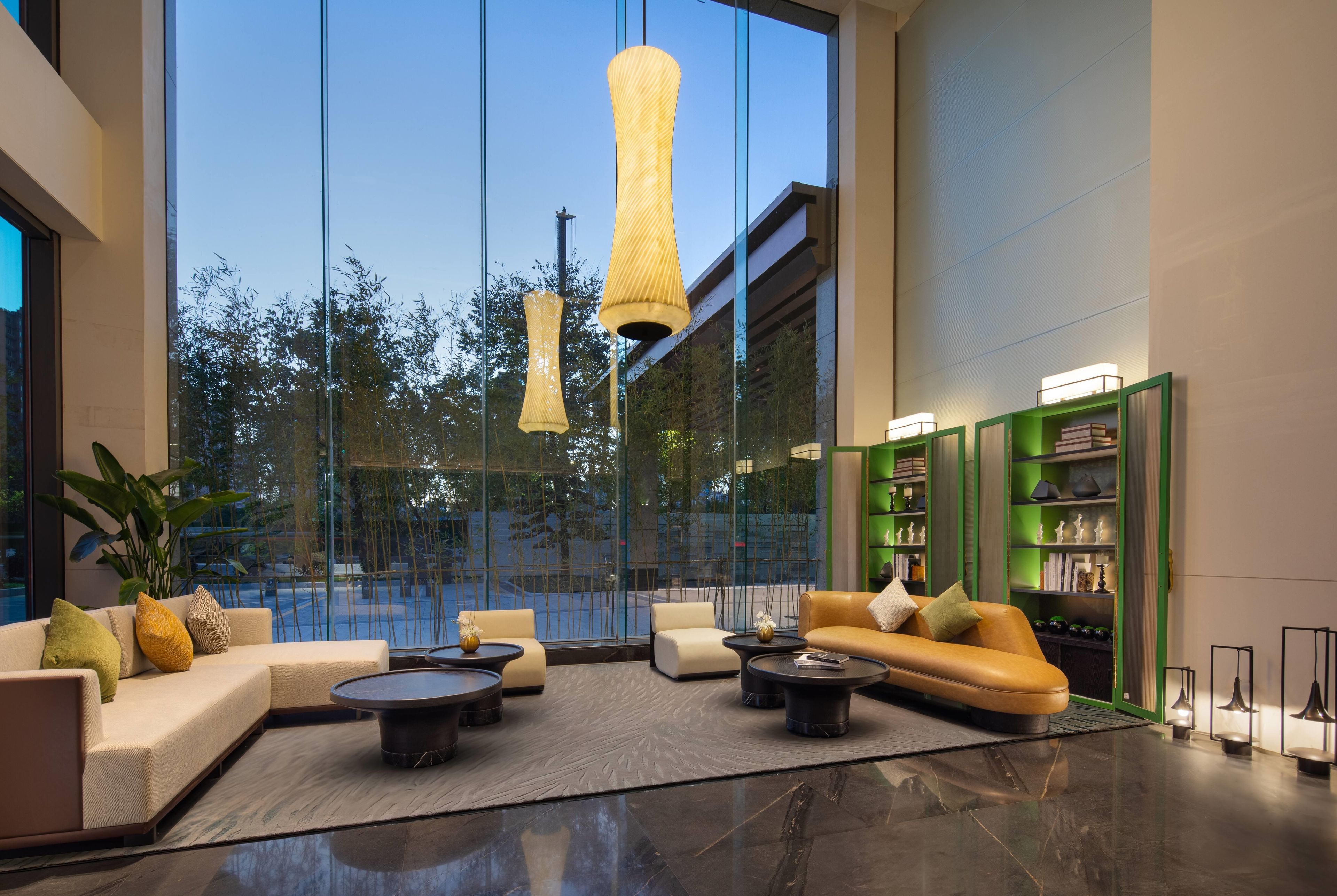 Un vestíbulo moderno con zona de estar, un muro de cristal con vistas y una estantería verde.