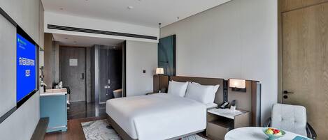 A hotel room with a bed, bedside tables, a desk, a chair, a TV, and a bathroom.