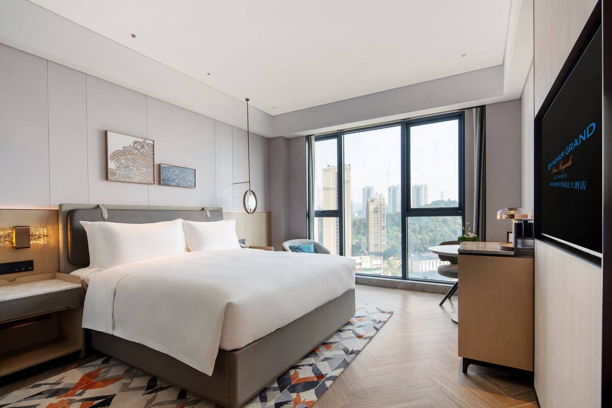 Una habitación de hotel moderna con una cama grande, un escritorio, una silla y un televisor.