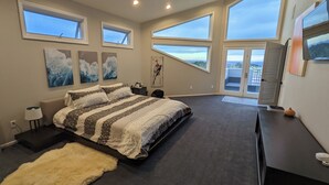 Een ruime slaapkamer met een groot bed, meerdere ramen en uitzicht op de omgeving.