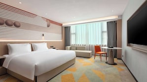 Una habitación de hotel moderna con una cama grande, un sofá, un televisor y una mesa de comedor.