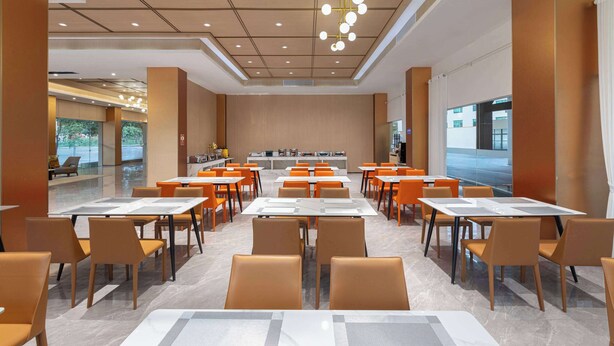 Un comedor espacioso con varias mesas y sillas, un diseño moderno de techo y vistas al exterior a través de amplias ventanas.