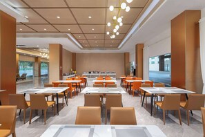 Un comedor espacioso con varias mesas y sillas, un diseño moderno de techo y vistas al exterior a través de amplias ventanas.
