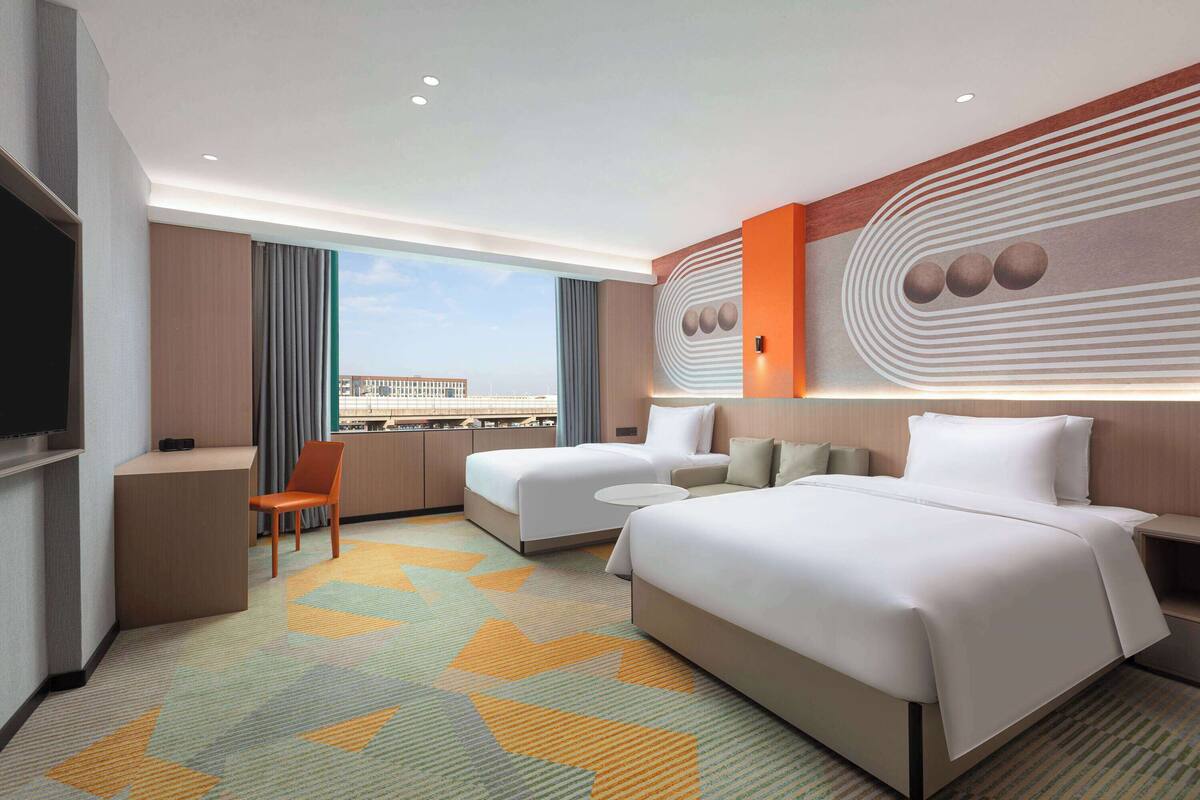 A hotel room with a large bed, a desk, a chair, and a TV.
