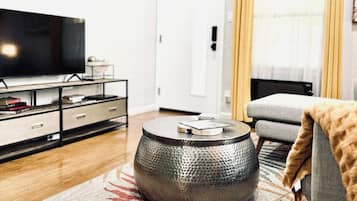 Una sala de estar moderna con una televisión de pantalla plana, una mesa redonda y un sofá.