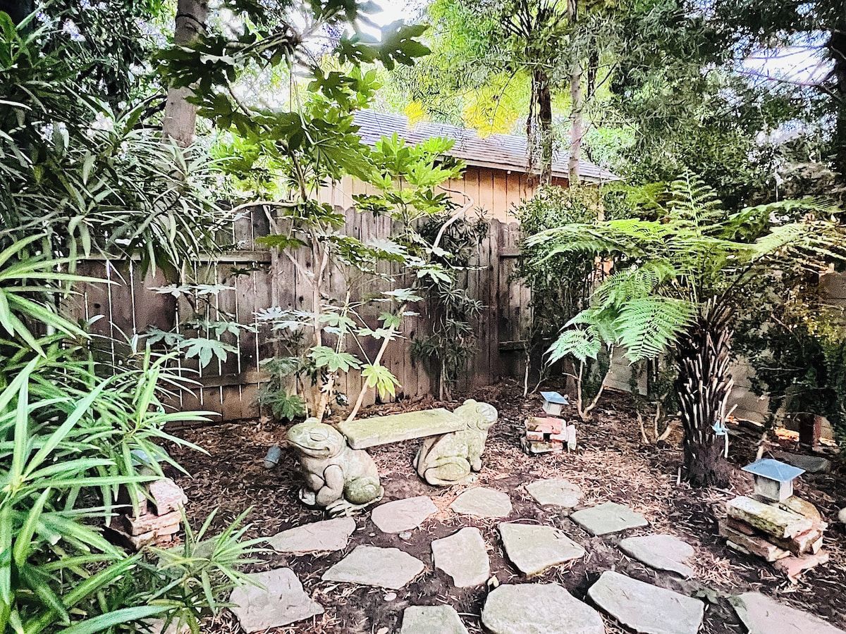 A garden with a stone pathway, a wooden fence, and a bench.