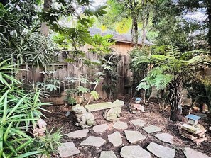 A garden with a stone pathway, a wooden fence, and a bench. - Historic Midtown Bungalow: Walk to Ice Blocks (Sacramento)