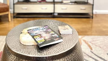 Una sala de estar con televisor, una mesa de centro con revistas y un adorno en la pared.