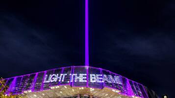 A modern building with a prominent vertical light feature and the text 'LIGHT THE BEAM' on the facade.