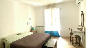A simple, well-lit bedroom with a single bed, a small table, a chair, and a globe on a nightstand. - Pannieri apartment  (Palermo)