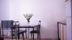 A dining area with a table, four chairs, a vase with flowers, a bookshelf, and a television. - Pannieri apartment  (Palermo)
