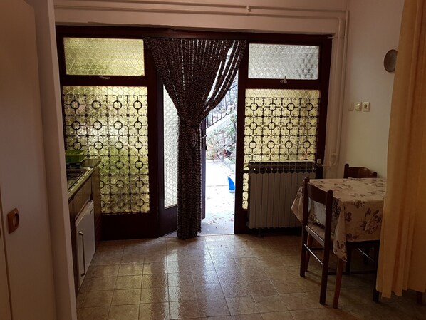 A kitchen with a tiled floor, a table with a floral tablecloth, and a chair.