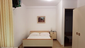 A bedroom with a bed, a nightstand, a painting on the wall, and a wardrobe. - Apartments Nives - Studio Apartment with Terrace (Mali Losinj)
