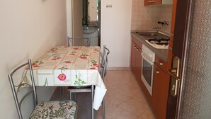 A compact kitchen with a dining table, chairs, a sink, and a stove.