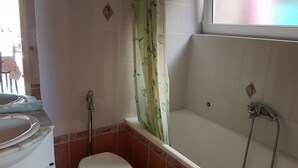 A bathroom with a toilet, a shower, and a sink.