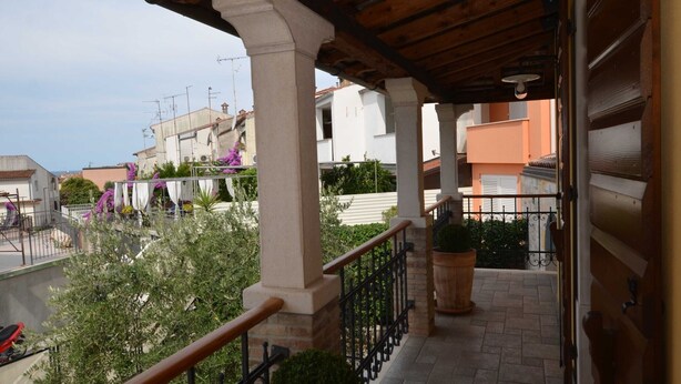 A covered balcony with a wooden ceiling, stone columns, and a metal railing. - Georgeous and Warm Living Downtown Rovinj - Standard Twin Room (Rovinj)