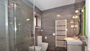 A modern bathroom with a glass shower enclosure, a bidet, a toilet, a sink with a mirror, and a towel rack. - Georgeous and Warm Living Downtown Rovinj - Standard Twin Room (Rovinj)