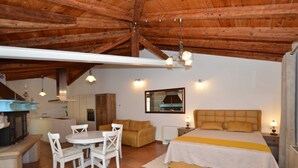 Una habitación amplia con una cama grande, una mesa de comedor con sillas, un sofá y una zona de cocina.