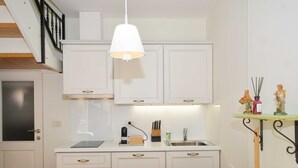 Une cuisine moderne avec des meubles blancs, une cuisinière encastrée, un évier et un coin repas doté d’une table blanche.