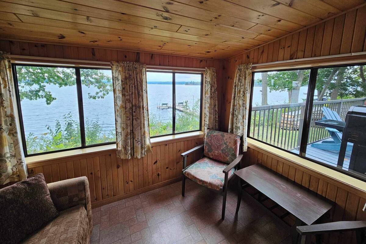 A cabin with wooden walls and a large window overlooking a lake.