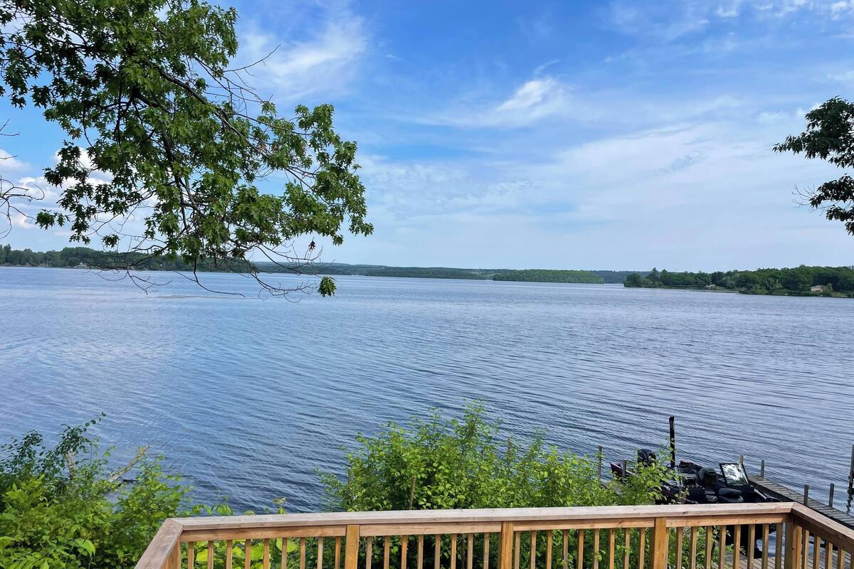 A wooden deck overlooking a calm lake with distant land and trees.