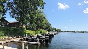 Un quai avec des bateaux, une maison et un ciel dégagé.