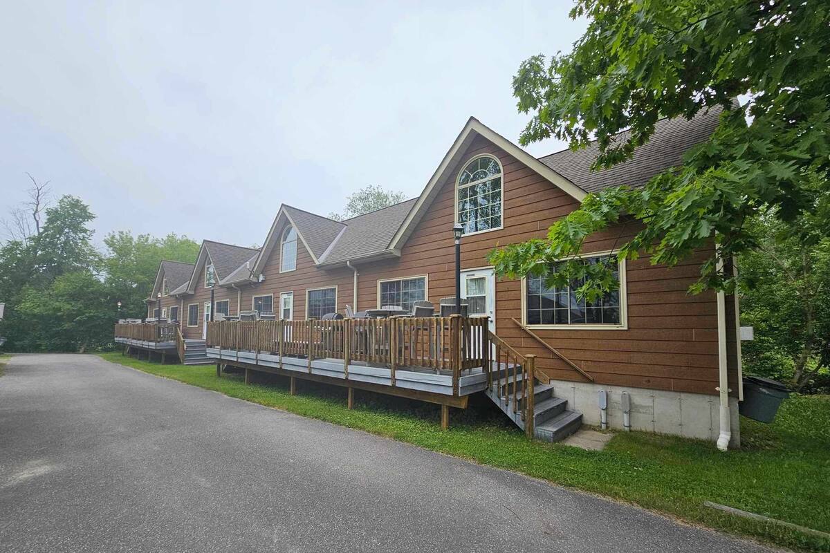 A row of cabins with a wooden deck and a covered outdoor area.