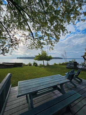 A wooden deck with a table and chairs overlooking a lake with a distant island. - Southview Cottages Resort (Bailieboro)