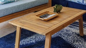 Ein Zimmer mit einem Bett, einem Nachttisch aus Holz, einer Lampe, einem kleinen Tisch mit einem Korb und einem blauen Teppich mit Muster.