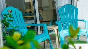 Eine Glastür führt zu einer Terrasse mit zwei türkisfarbenen Stühlen und einem kleinen Tisch.