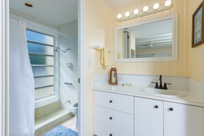 Une salle de bain équipée d’une douche, de toilettes, d’un lavabo et d’un meuble-lavabo.