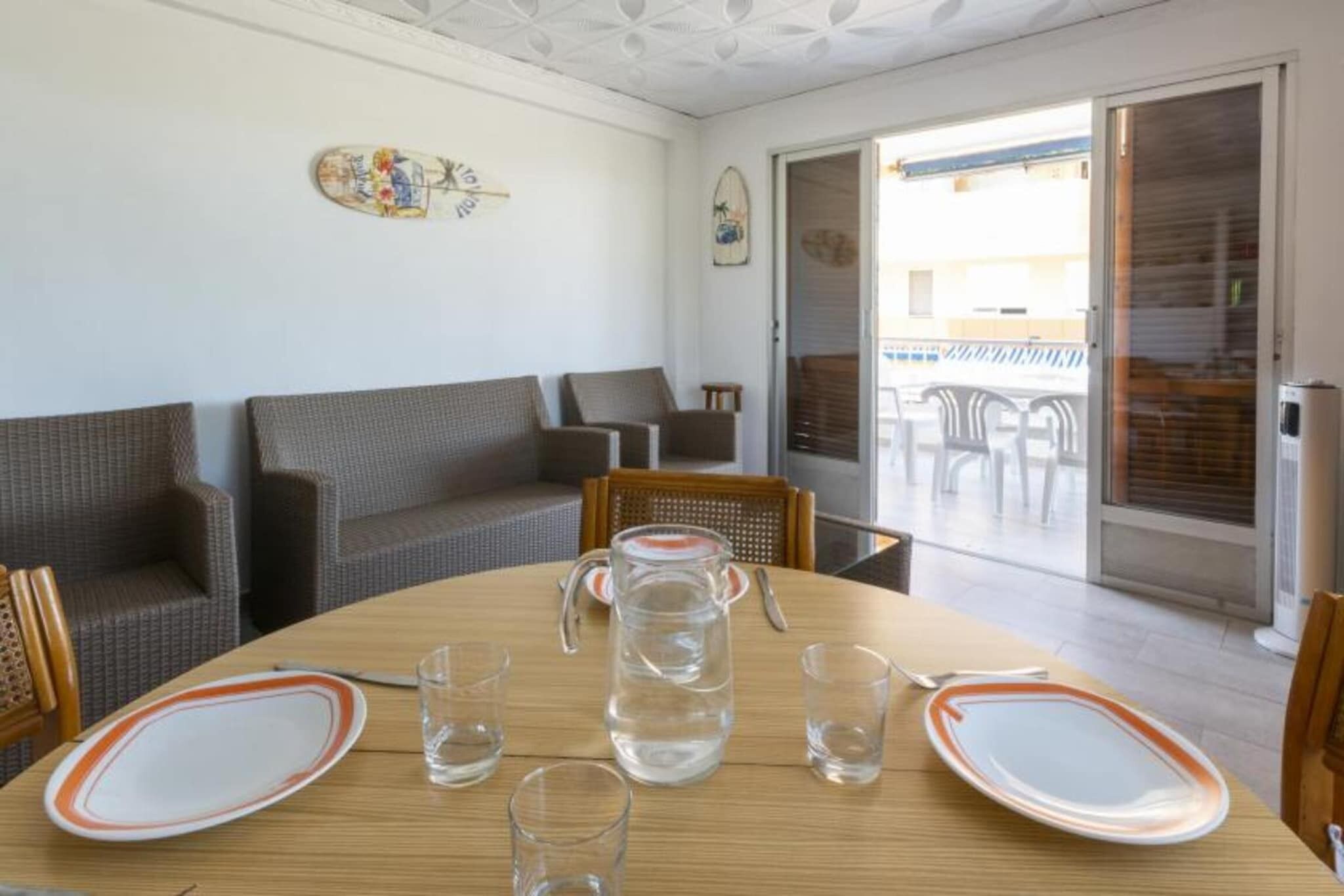 Una zona de menjador amb una taula de fusta preparada per a dues persones, una gerra d'aigua i dos plats.
