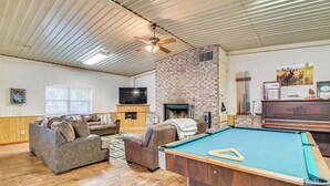 A living room with a pool table, sofas, a fireplace, and a television. - Riverfront Fishing: Home in Columbus w/ Grill (Columbus)