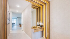 Un couloir moderne agrémenté d’un miroir à cadre en bois et d’une console en bois sur laquelle sont disposés des objets décoratifs.
