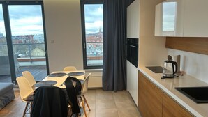 A modern kitchen with a dining area, large windows with curtains, and a view of the city. - Brabank 457 BestView by Grand Apartments (Gdansk)