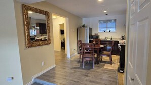 Una cocina moderna con comedor, piso de madera y un espejo grande en la pared.