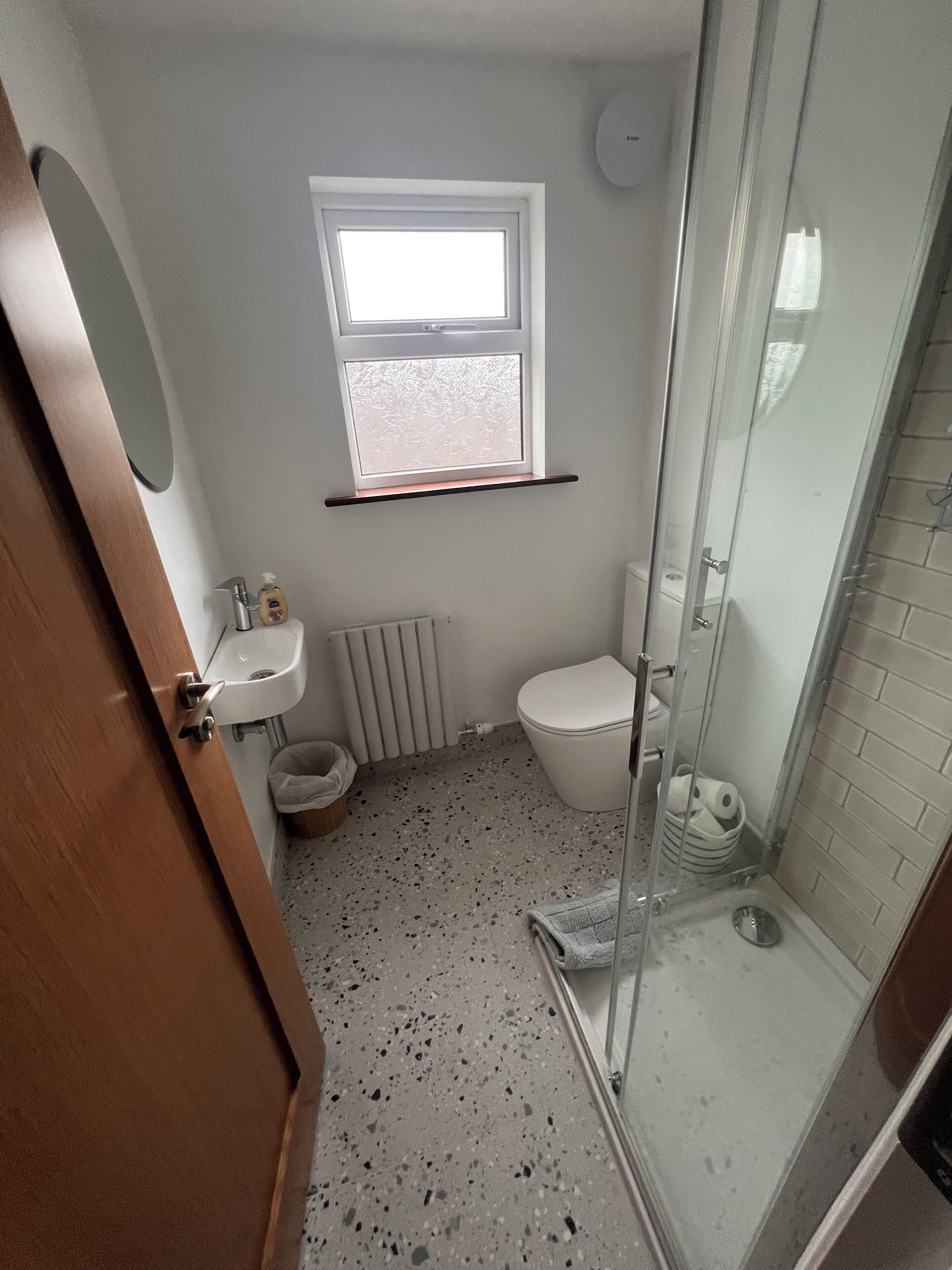 Un baño pequeño con ducha, inodoro, lavamanos y ventana.