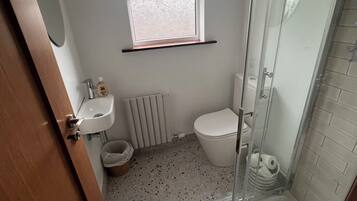 Un baño pequeño con ducha, inodoro, lavamanos y ventana.