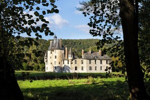 A large, historic stone building with multiple towers and a well-maintained lawn in front.